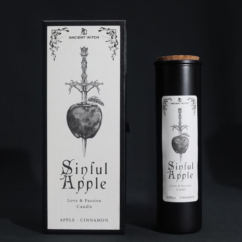 Sinful Apple rituální svíčka a dárková krabička s jablkem propíchnutým athamou na černém pozadí